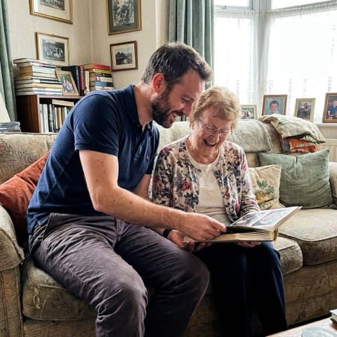 Professional caregiver sharing a warm moment looking at a photo album with an elderly client, representing compassionate home care services